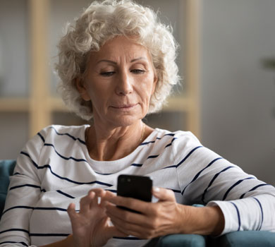 older woman using mobile phone to access crossroads online banking app