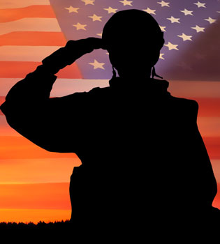silhouette of a soldier saluting with a flag in the skyline