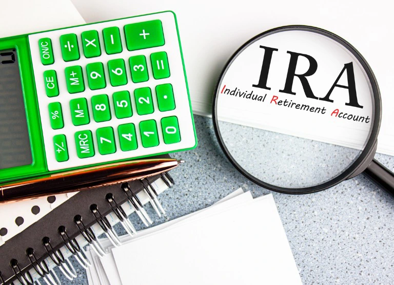 Calculator and magnifying glass on IRA on top of desk