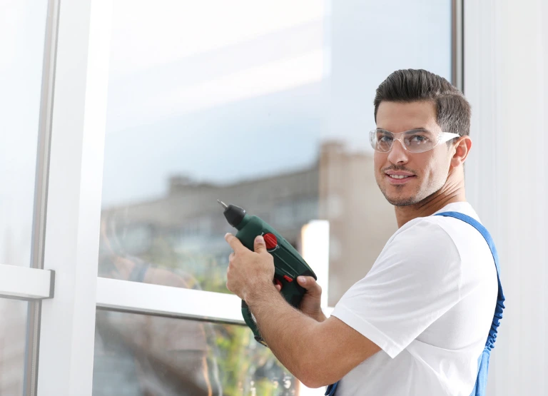 man with safety glasses, holding drill while making some repairs on his home