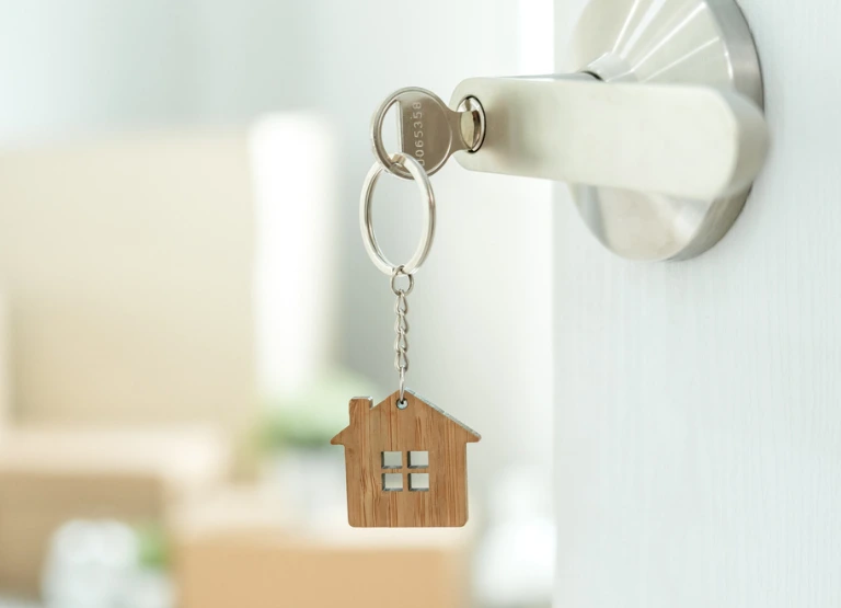 close up of key and wooden home shape keychain in door lock